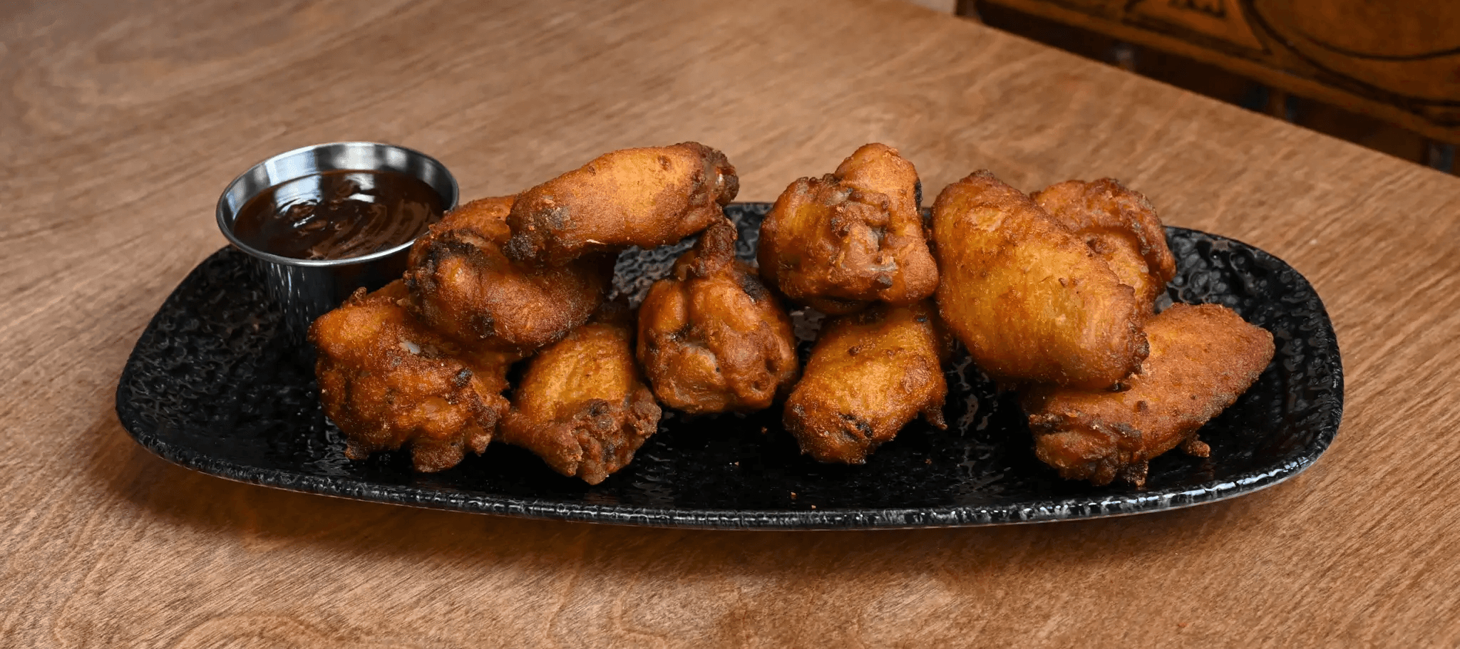 Fried appetizer bites served on a black platter