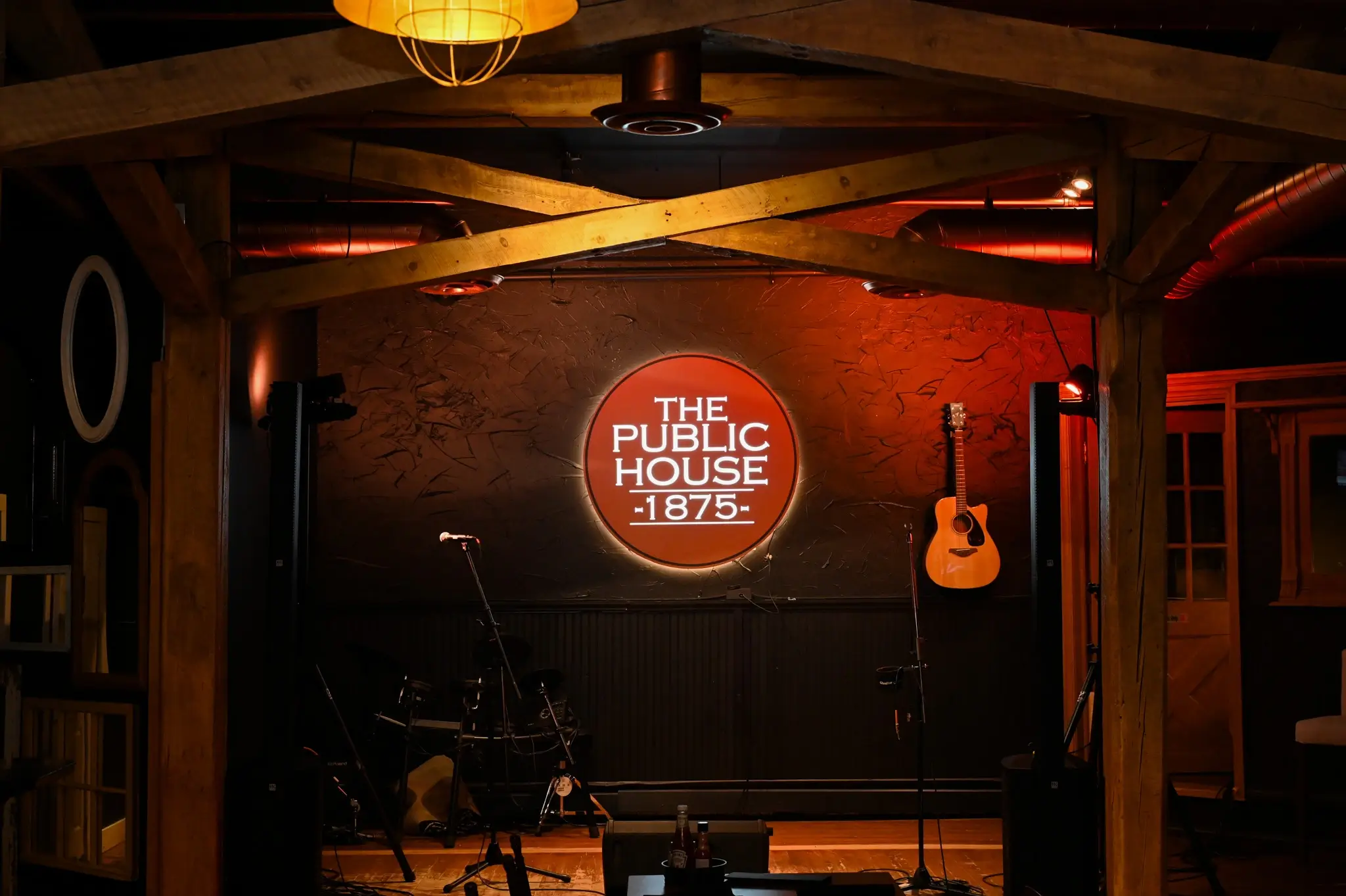 Warmly lit Public House stage with instruments and signage